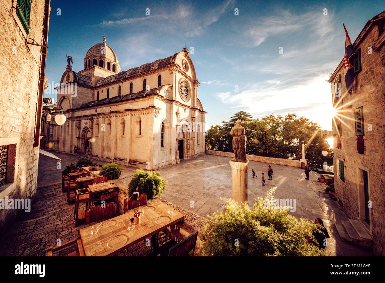 Vue sur la cathédrale de assorti James projetant une ombre sur la place avec des tables et des chaises, des statues, et des gens profitant de la journée ensoleillée, Šibenik, Šibenik Banque D'Images