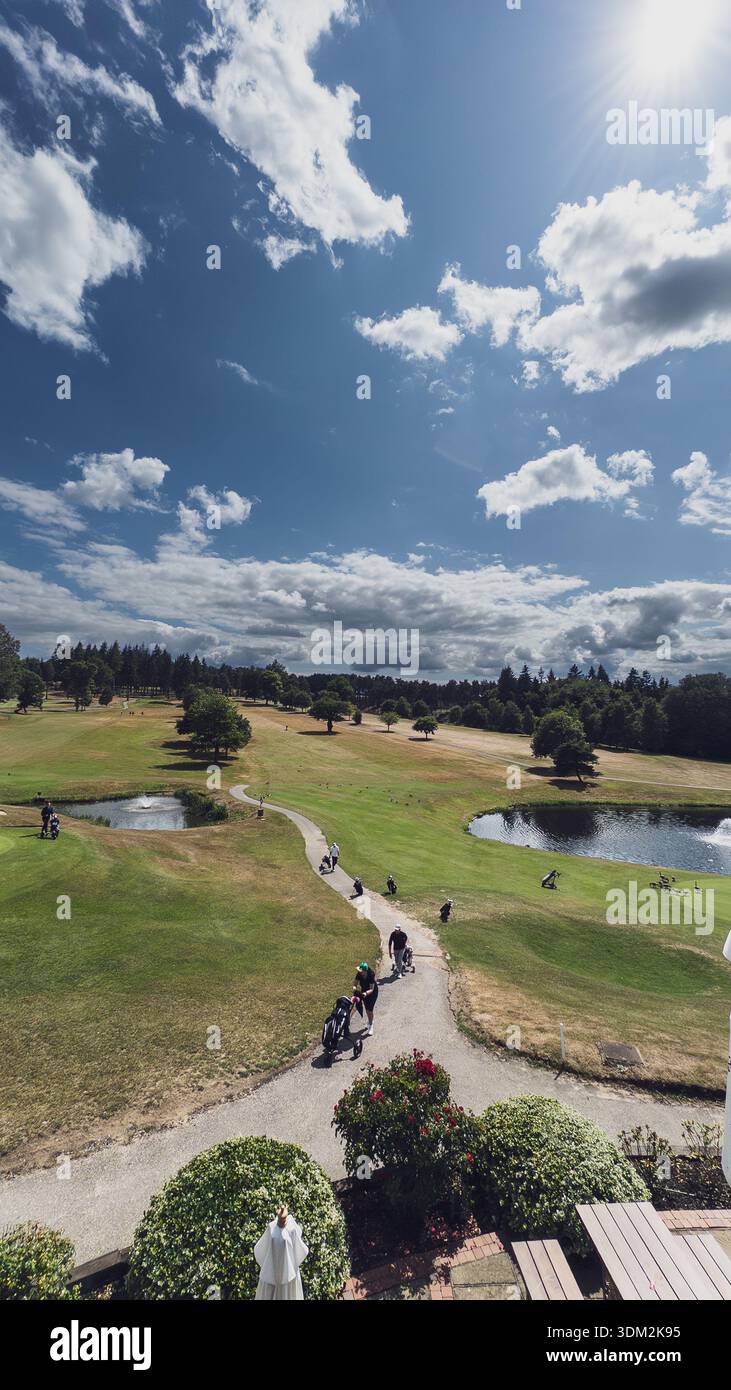 Vue aérienne sur le terrain de golf luxuriant avec étangs, fairways, golfeurs, pins, buissons fleuris et ciel bleu ensoleillé Banque D'Images