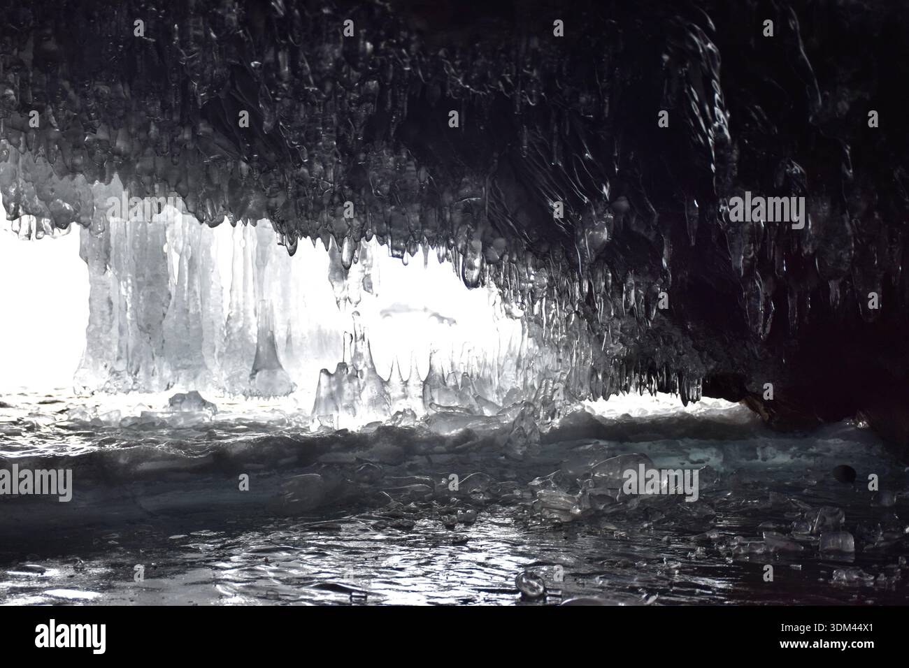 Grotte de glace gelée sur le lac Baïkal en hiver, des glaçons imposants et des murs de glace lisses formant une chambre naturelle spectaculaire le long du rivage rocheux. Banque D'Images