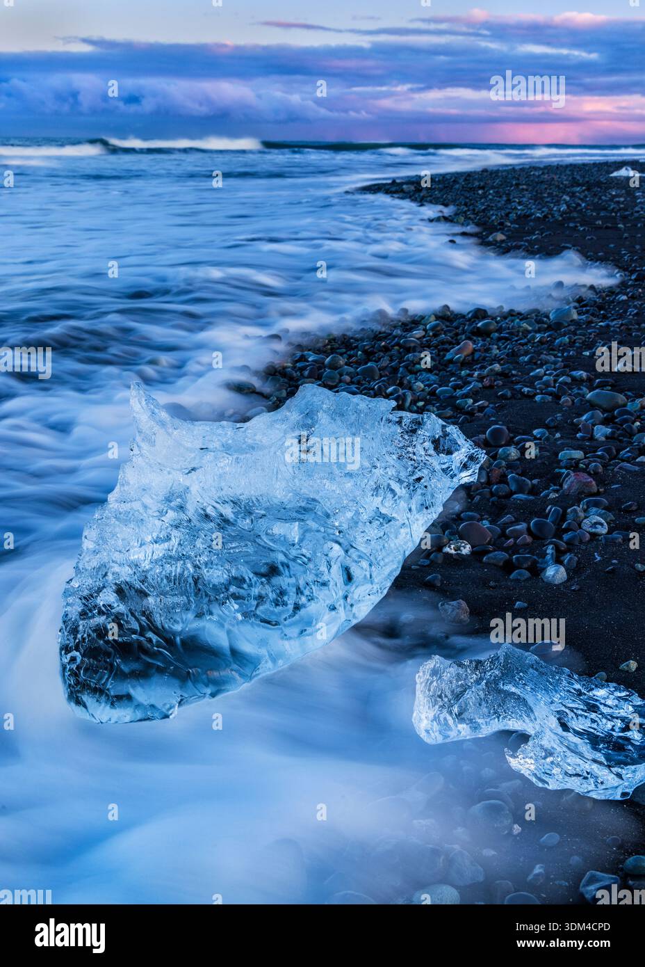 Deux morceaux de glace cristalline entourés de marées moussantes sur Diamond Beach près du lagon glaciaire de Jökulsárlón dans le sud de l'Islande. Banque D'Images