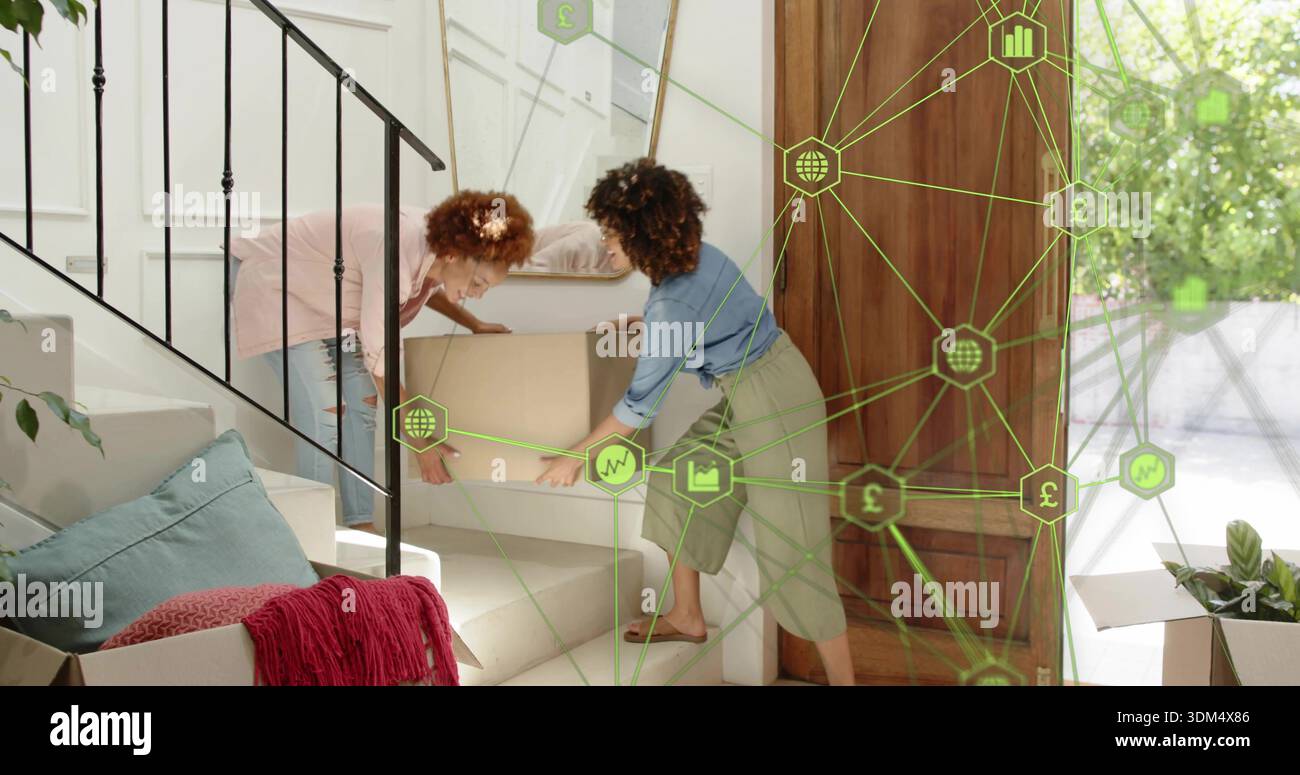 Déménagement de deux femmes en chaussettes portant la boîte de déménagement dans les escaliers moquettés à la maison, avec recouvrement vert Banque D'Images