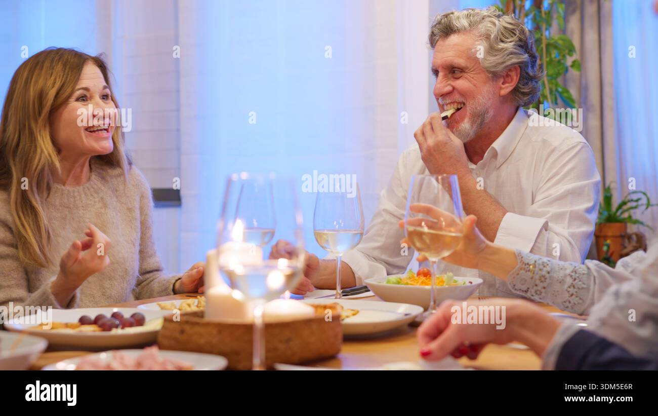 Amis seniors appréciant le dîner en riant en buvant du vin Banque D'Images