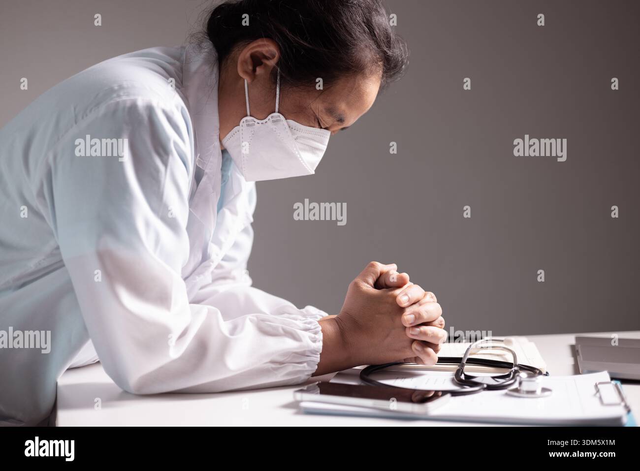 Femme prie avec ses mains serrées, croyant aux soins des médecins et des professionnels de la santé comme elle fait face à la maladie dans un hôpital ou une clinique, confiante Banque D'Images