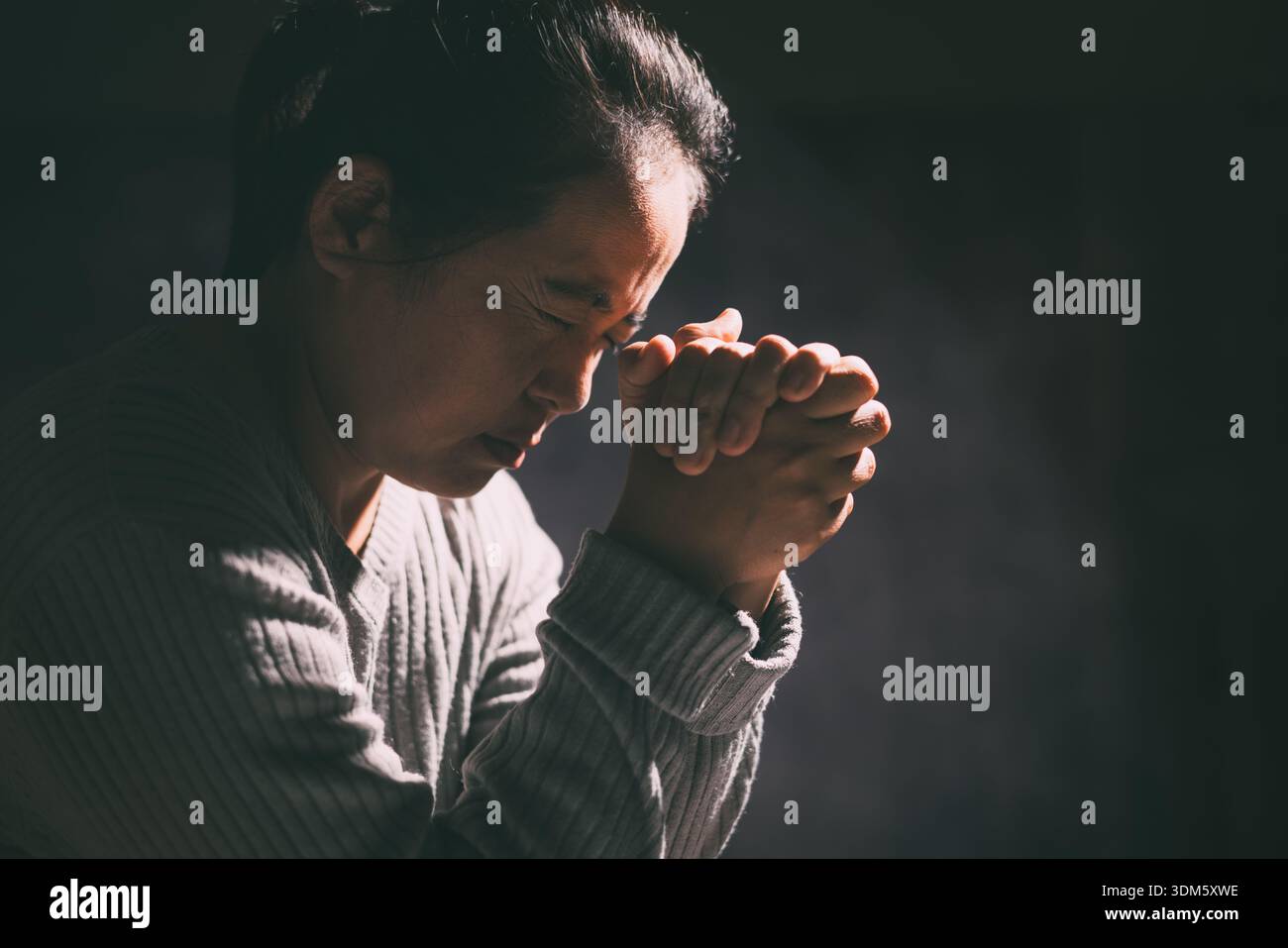 La femme a serré ses mains dans la prière, remplie de foi et d'espérance, croyant en Jésus Christ, et cherchant la sainte présence de Dieu à travers ses prières Banque D'Images