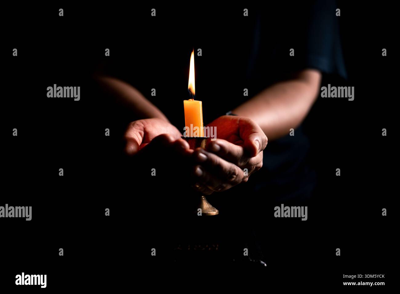 Dans l'obscurité, la main serrée dans la prière, éclairée par la douce lumière des bougies, tandis que les flammes noires du feu des bougies scintillent doucement. bougie, prier, main, prière, Banque D'Images