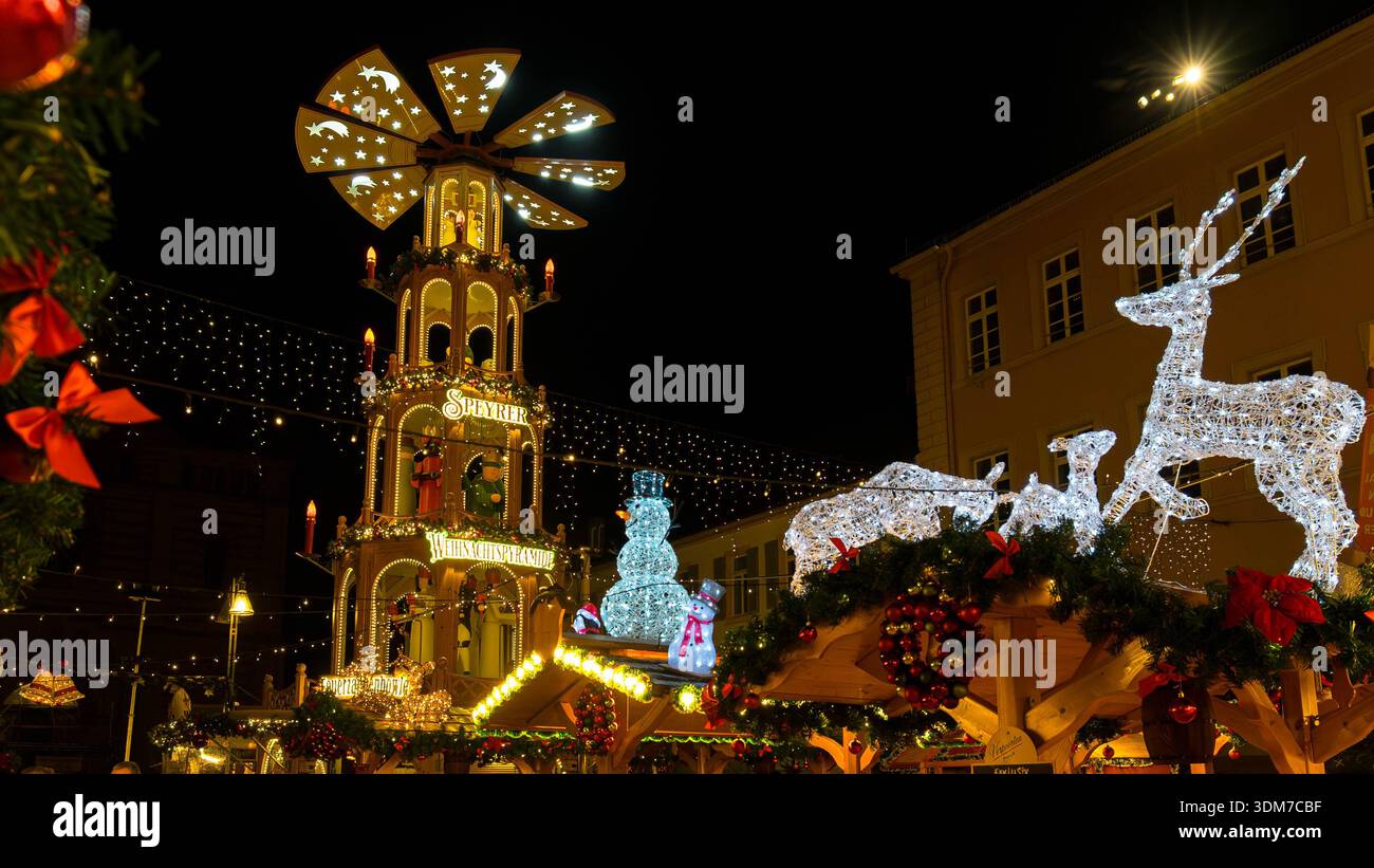 Pyramide de Noël allemande traditionnelle illuminée avec cloches d'or et arc rouge festif au marché nocturne Banque D'Images