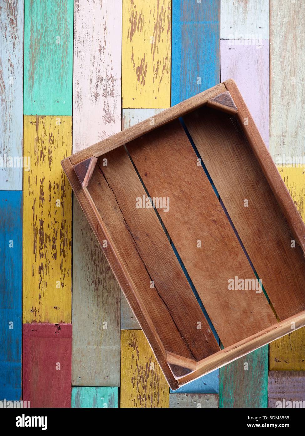 Caisse en bois rustique vide sur fond en bois peint coloré, vue de dessus plat Banque D'Images