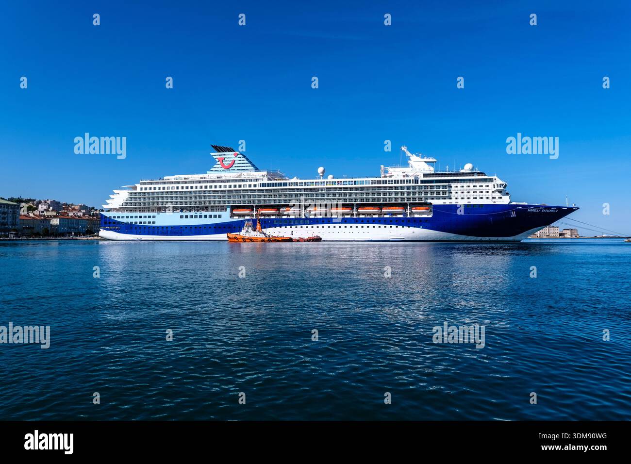 Le bateau de croisière Marella Explorer 2 au port de Trieste avec le phare Lanterna di Trieste au loin. Banque D'Images