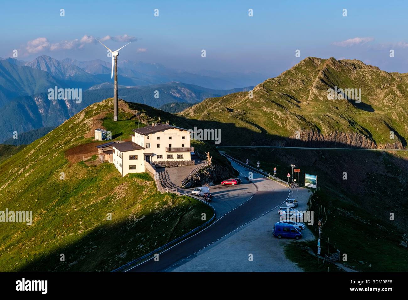 Penser Joch Pass avec la cabane de montagne Gasthof Alpenrose et une éolienne. Hautes montagnes au loin. Banque D'Images