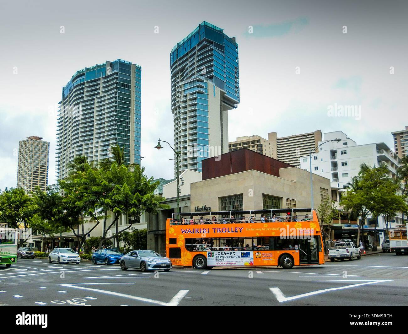 Un bus de style hawaïen connu sous le nom de trolley descend la rue principale de Kalakaua Avenue à Waikiki Banque D'Images
