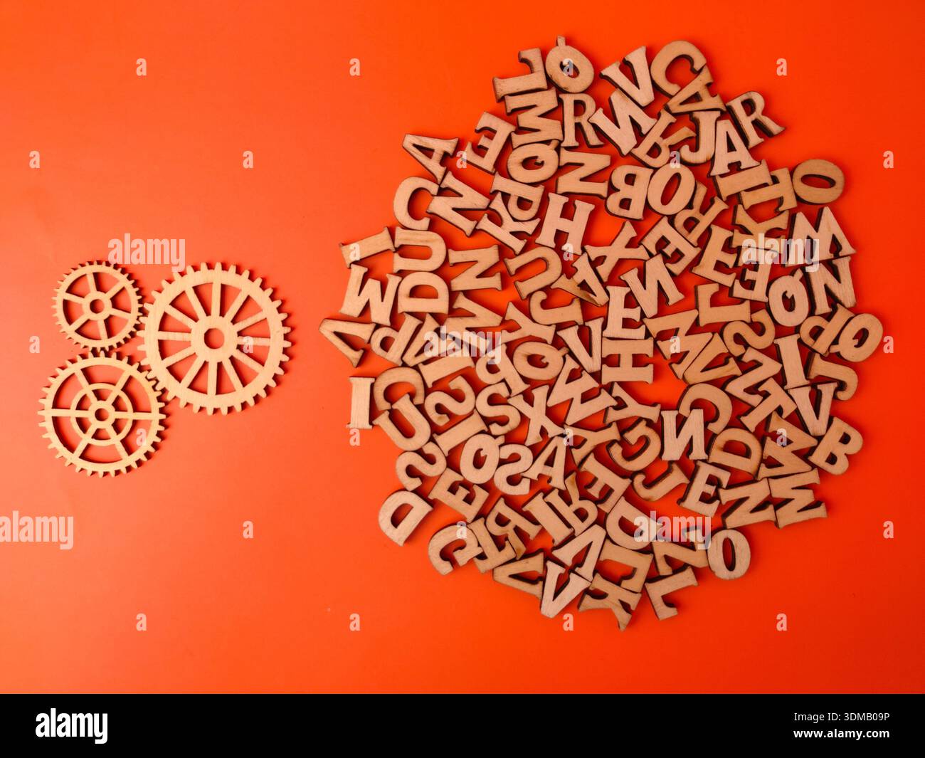 Lettres de l'alphabet découpées en bois et formes d'équipement sur fond orange. Banque D'Images