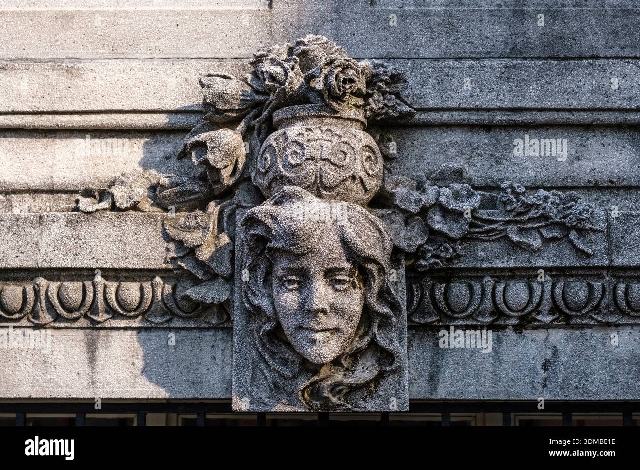 Gros plan d'un relief en pierre Art Nouveau avec un visage féminin et des éléments floraux sur une façade de bâtiment. Banque D'Images