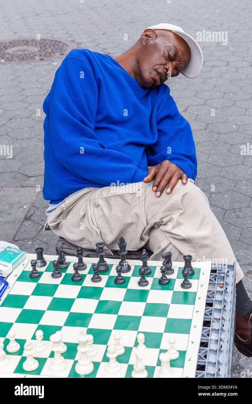 Fatigué d'attendre un adversaire qui ne s'est jamais présenté, ce joueur d'échecs s'est finalement endormi devant son échiquier. Union Square Park, New York ci Banque D'Images