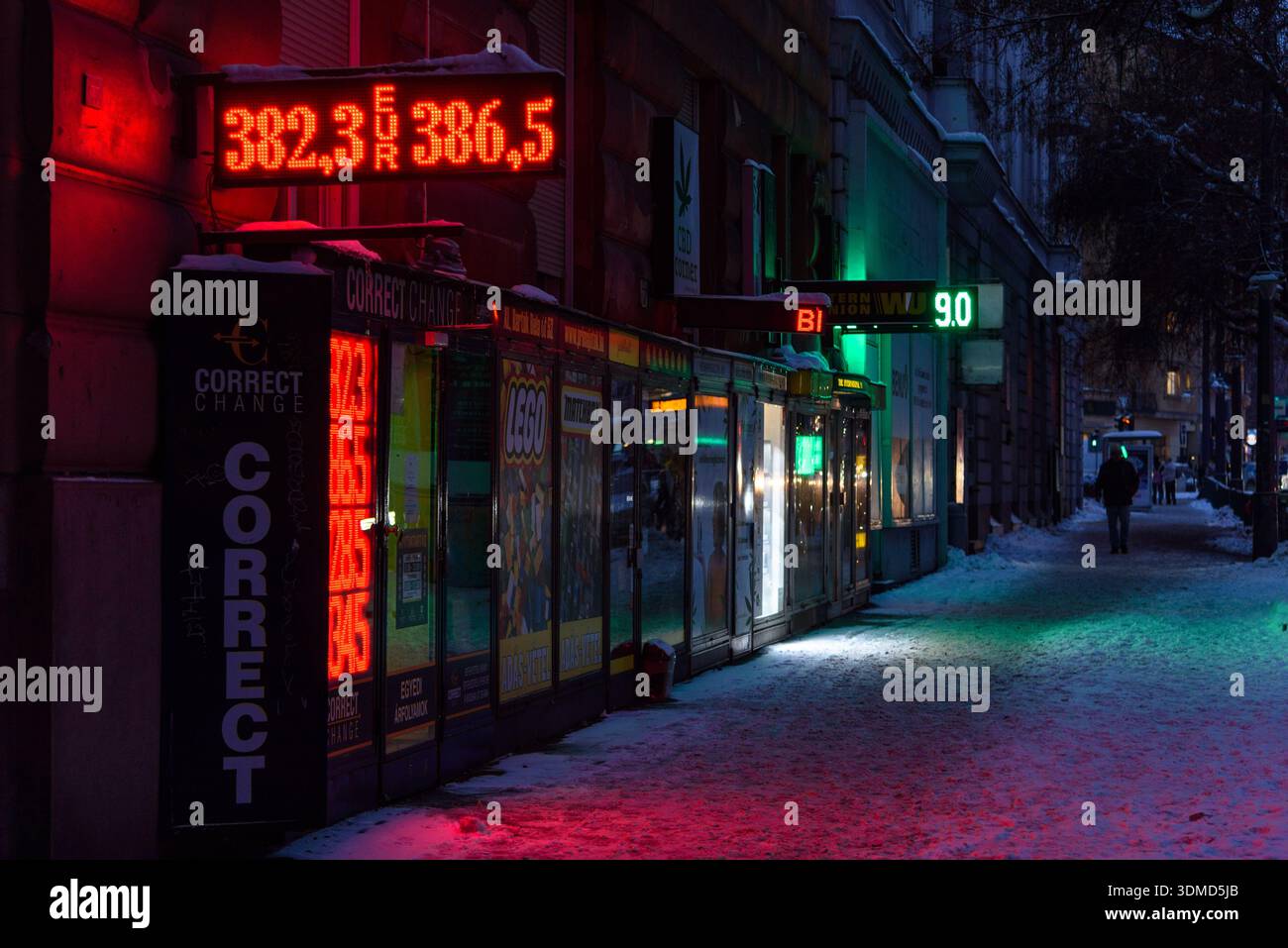 Les lumières LED d'un bureau de change font briller le trottoir de neige à Budapest, en Hongrie Banque D'Images
