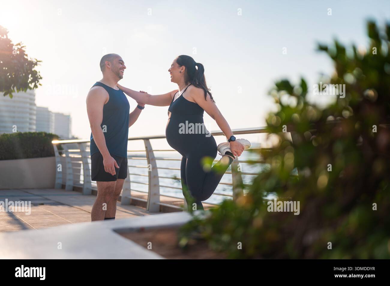 Un couple participe à une séance d'étirements au bord de l'eau, montrant leur engagement envers la forme physique et la santé tout en chérissant leurs moments spéciaux t Banque D'Images
