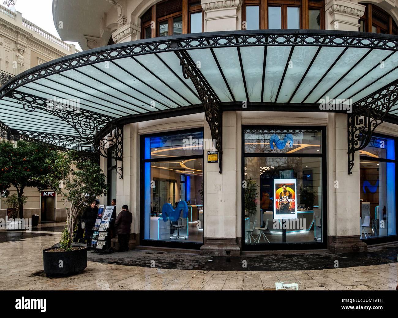 Devanture moderne de télécommunications Movistar avec éclairage au néon bleu sous un auvent en fer forgé orné dans le centre historique de Valence, en Espagne. Banque D'Images