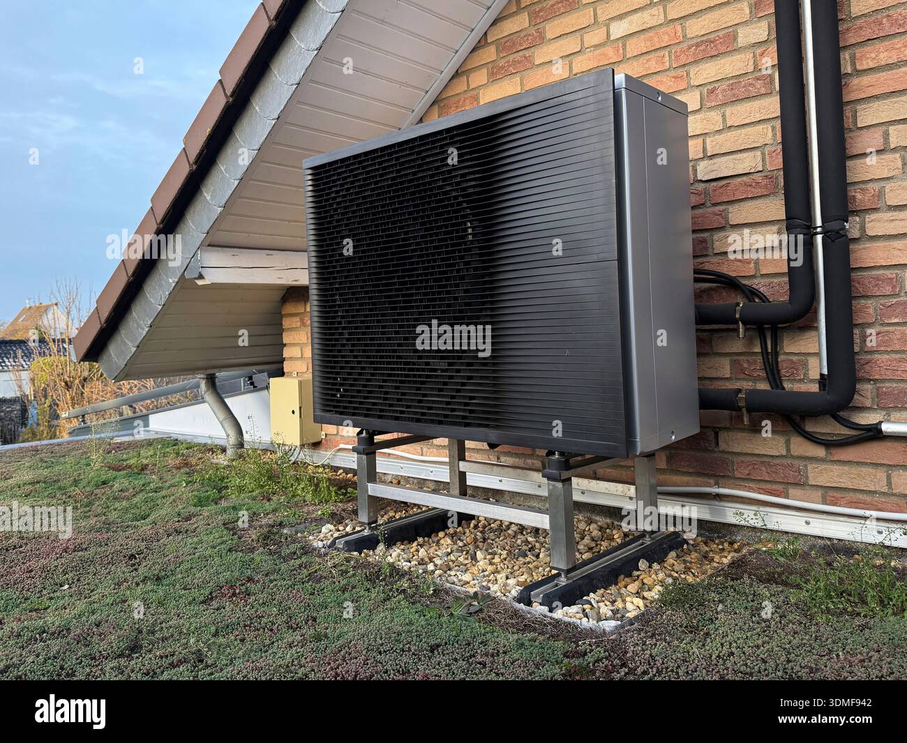 Pompe à chaleur air-eau, mur de briques, toit vert Banque D'Images