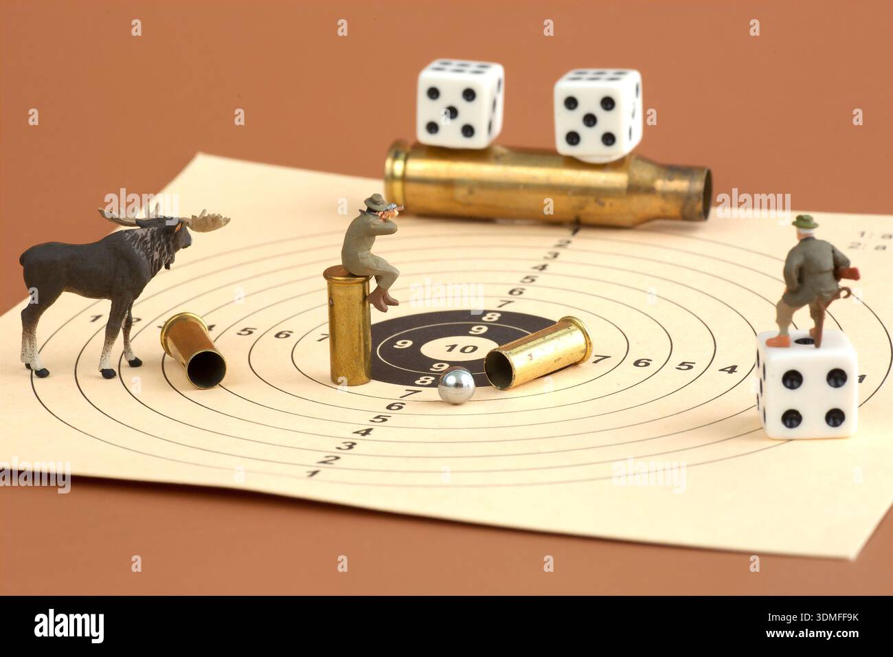 Des chasseurs miniatures et des orignaux disposés sur une cible de tir avec des munitions et des dés dans une nature morte conceptuelle. Banque D'Images
