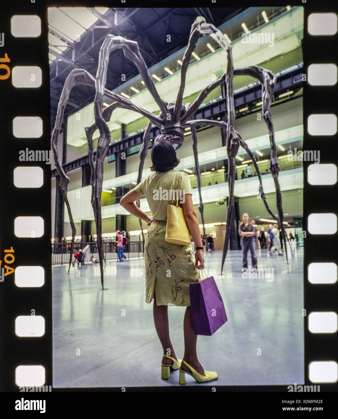 Une jeune femme se tient en contemplation devant Maman (1999), la sculpture emblématique de Louise Bourgeois de 9 mètres de haut d'une araignée installée dans la Tate Modern. Banque D'Images
