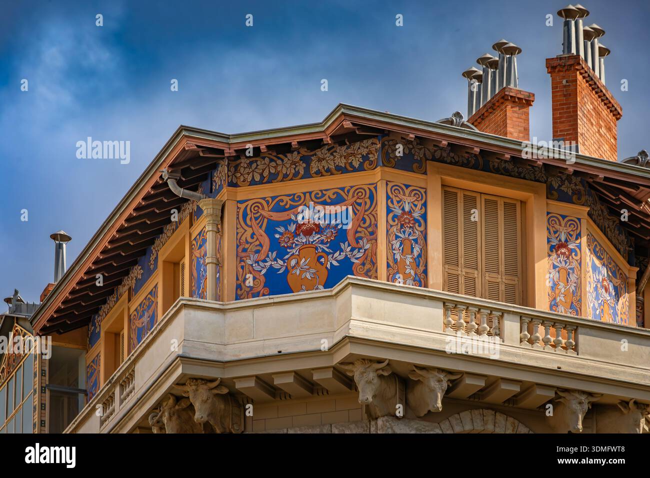 Bâtiment belle Epoque orné de fresques Sgraffito florales bleues et dorées et de sculptures en tête de taureau en pierre soutenant un grand balcon à Nice, France Banque D'Images
