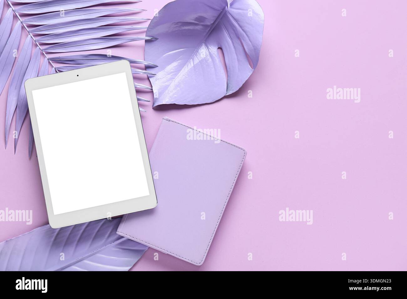 Ordinateur tablette, feuilles tropicales peintes et cahier sur fond rose, gros plan Banque D'Images