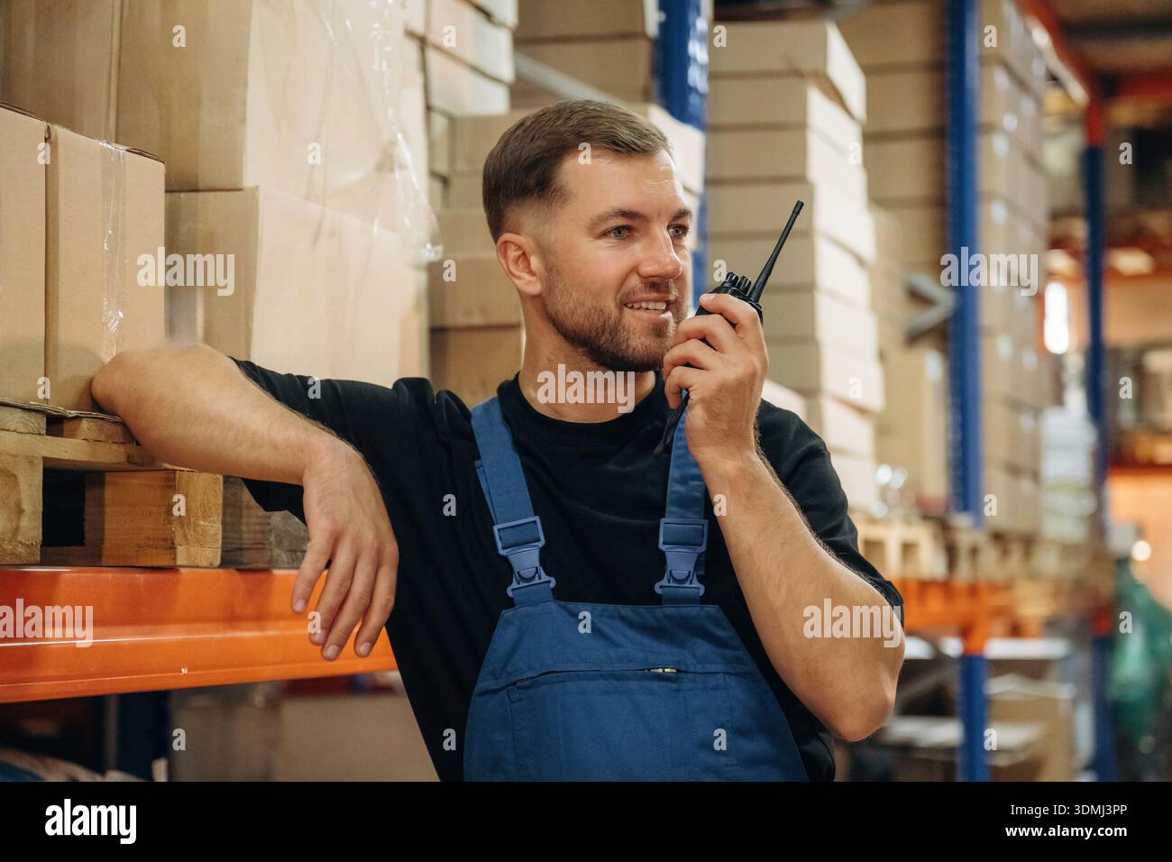 Conversation à l'aide d'un talkie-walkie. L'homme en uniforme travaille dans le stockage avec des colis pour l'expédition. Banque D'Images