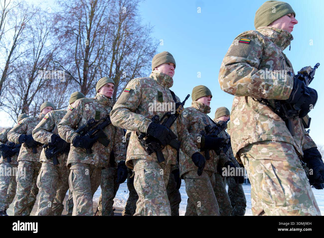 Des soldats lituaniens en hiver camouflent marchant avec des fusils sous un ciel bleu clair. Banque D'Images
