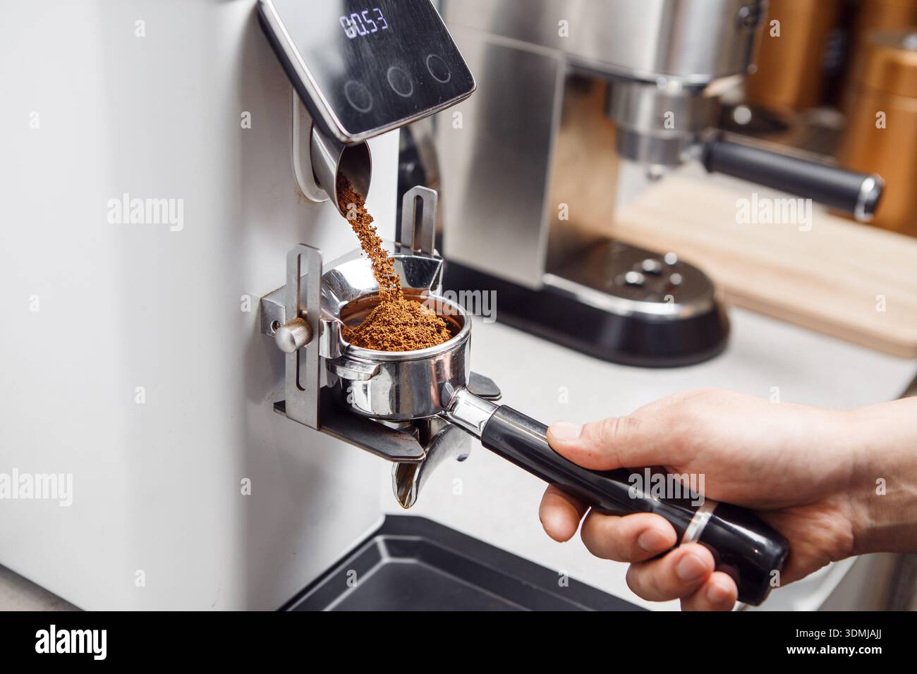 Café fraîchement moulu versé dans le porte-filtre du poste espresso Banque D'Images