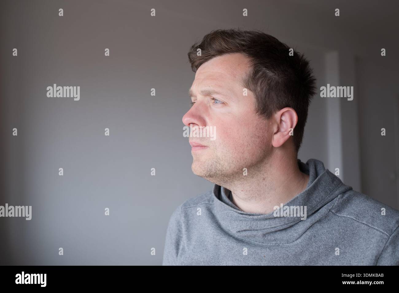 Jeune homme réfléchi avec le visage illuminé regardant loin et rêvant de l'avenir Banque D'Images