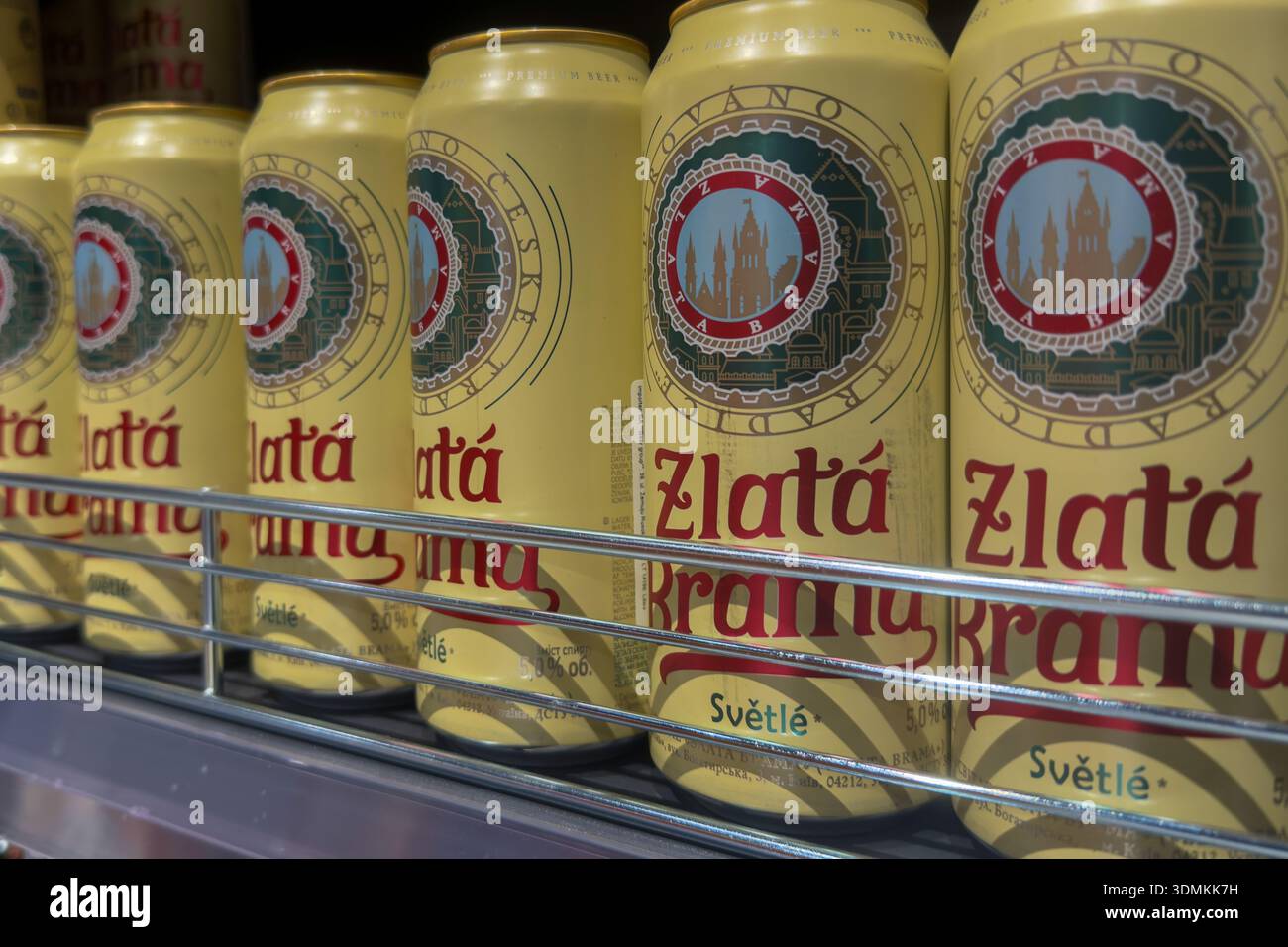 Poznan, Pologne - 22 novembre 2025 : les canettes de bière en aluminium Zlata Brama jaune vif, avec le design emblématique de l'étiquette du château de Prague, sont soigneusement stockées sur superm Banque D'Images