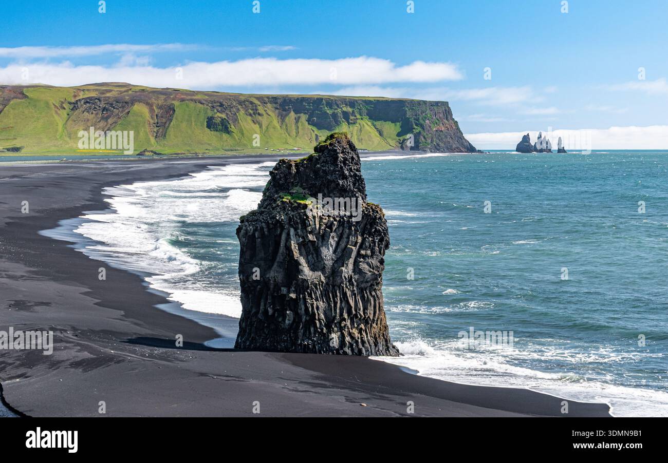Arnardrangur, une pile de basalte située sur le sable noir de la plage de Reynisfjara près de Vik dans le sud de l'Islande, avec des piles de Reynisdrangar à l'arrière Banque D'Images