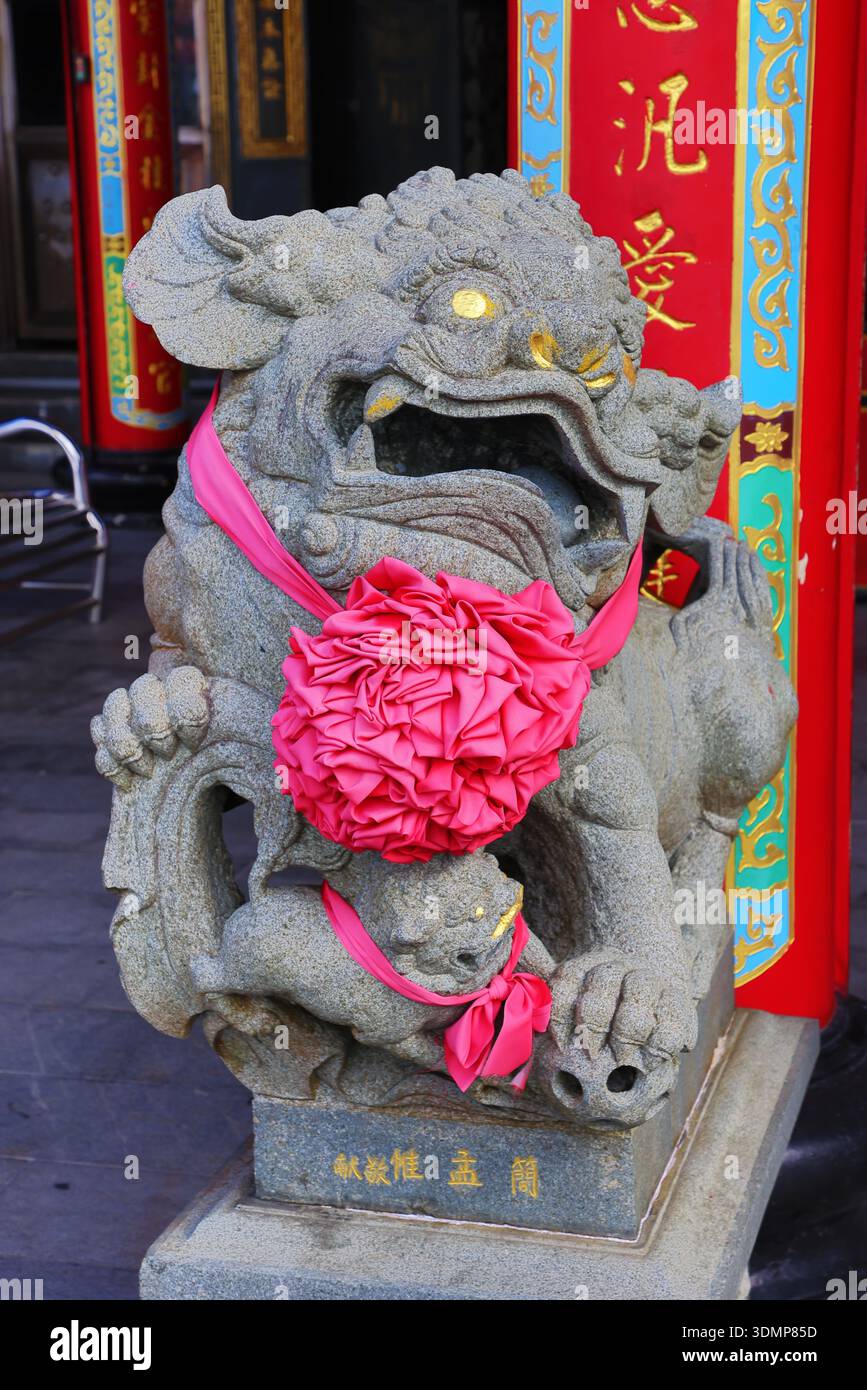 Statue de lion gardien appelé chien fu avec ruban rouge, à l'extérieur du temple taoïste Shengming à Jiufen, Taiwan ROC Banque D'Images