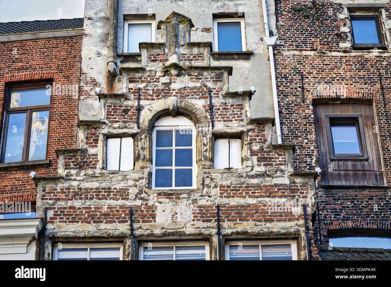 Mélange inhabituel d'un pignon historique en brique, de fenêtres modernes et de plâtre altéré sur un ancien bâtiment à Anvers, en Belgique. Une étude de la décomposition urbaine Banque D'Images