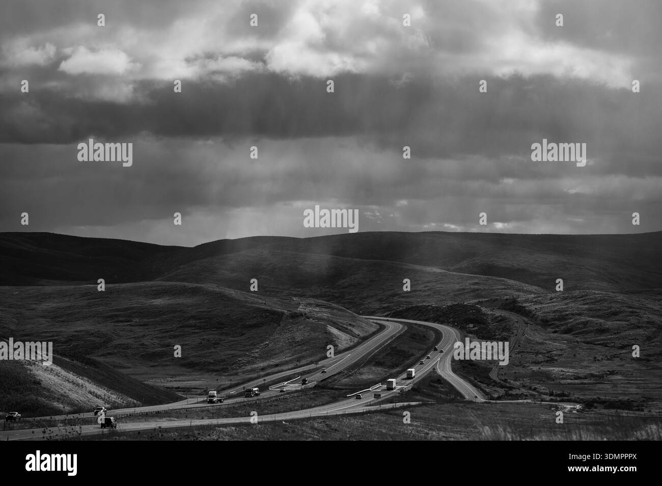 Les voitures et les camions de transport semi-remorques traversent les prairies et les prairies ouvertes avec un ciel spectaculaire après une tempête majeure le long de l'Interstate 84 Banque D'Images