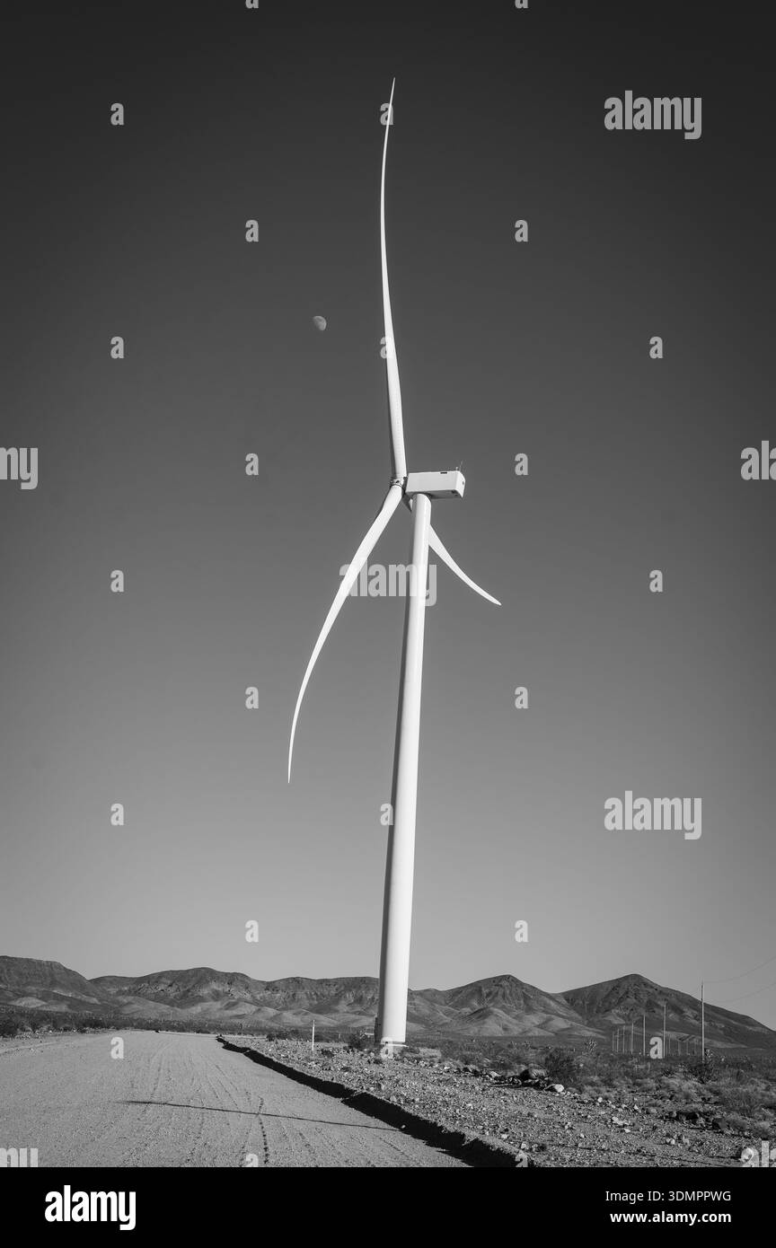 Un moulin à vent électrique géant avec la lune montrant à travers ses pales. Un parc éolien solaire entre Kingman AZ et Las Vegas Nevada. Noir a Banque D'Images