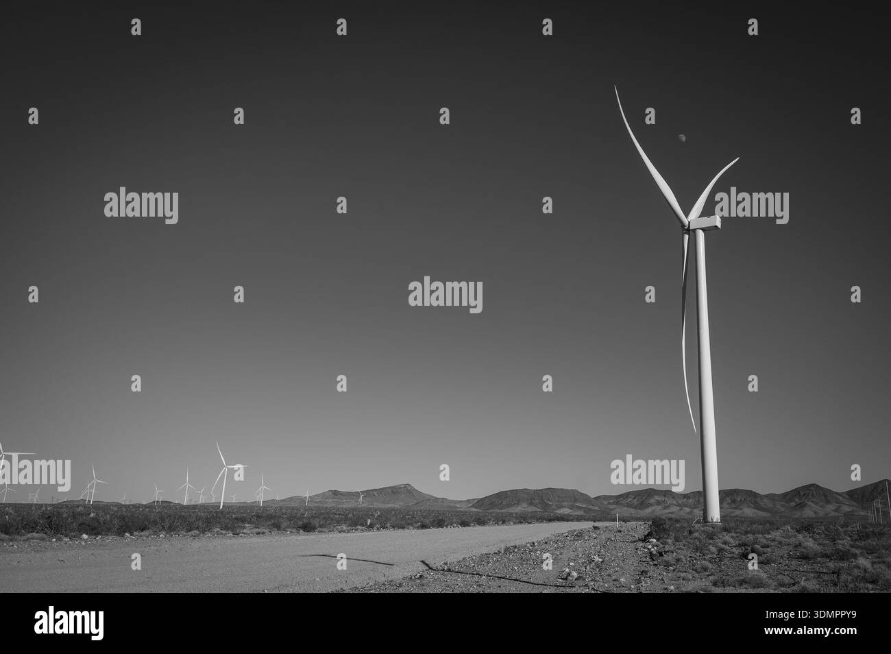 Un moulin à vent électrique géant avec la lune montrant à travers ses pales. Un parc éolien solaire entre Kingman AZ et Las Vegas Nevada. Noir a Banque D'Images