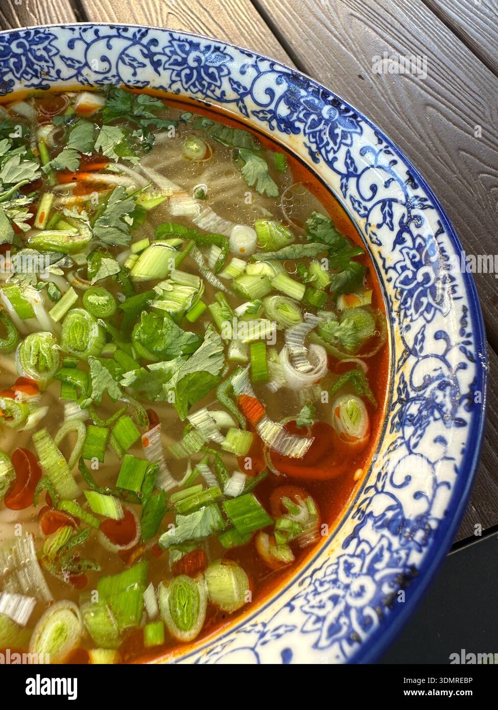 Un bol de soupe de nouilles de bœuf Lanzhou dans un bouillon bien épicé garni de tendre cubes de bœuf, d'oignon vert, de carotte blanche et d'huile de Chili comme petit déjeuner à Lanzhou Banque D'Images