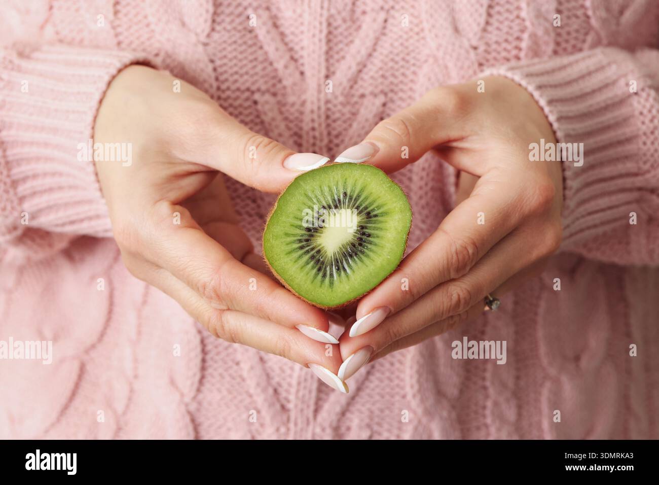 Femme tenant des kiwis dans un geste de mains en forme de coeur. Nutrition saine et concept de vitamine naturelle avec des aliments tropicaux frais à l'intérieur. Banque D'Images