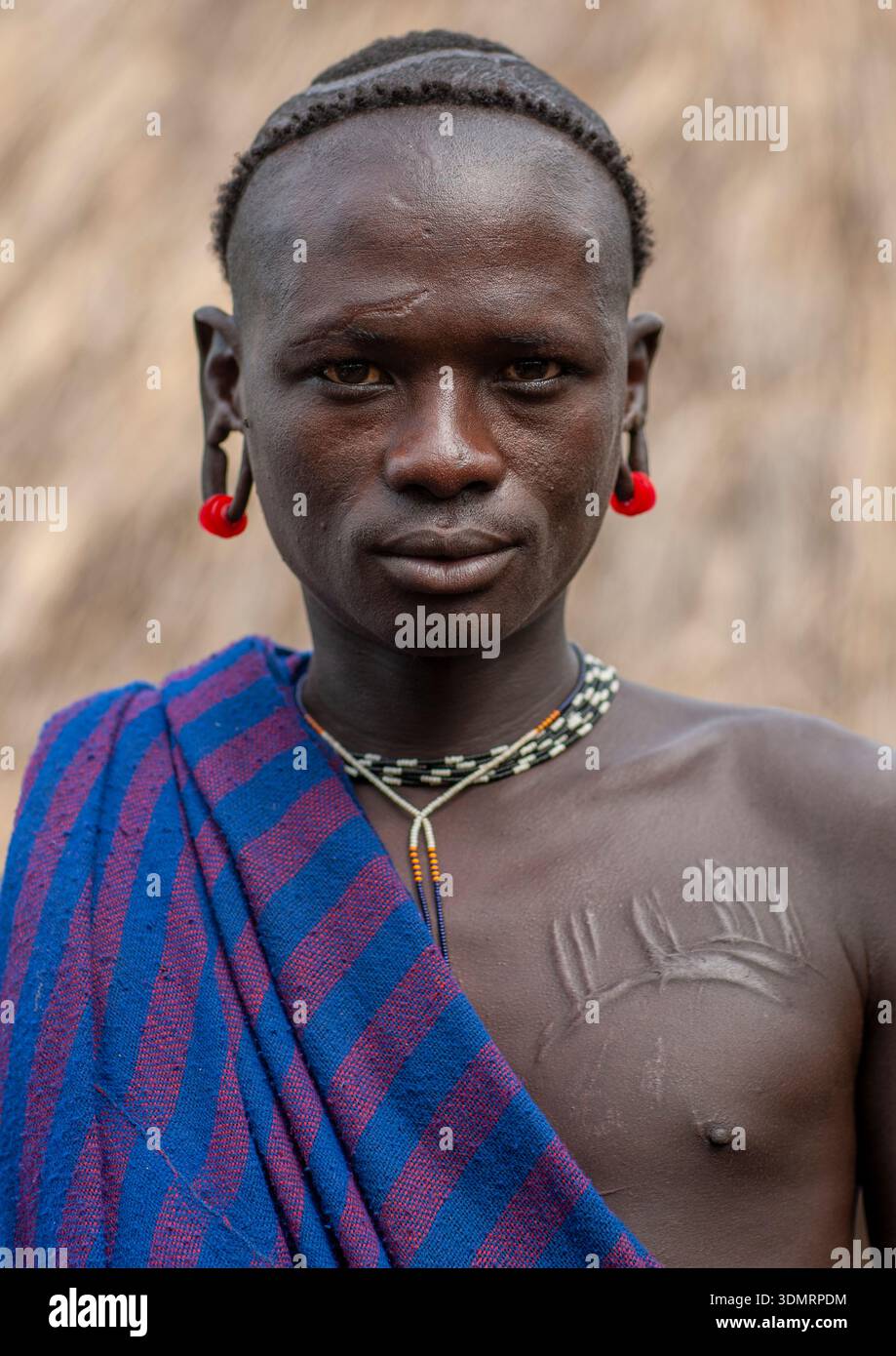 Homme de la tribu Surma avec oreille élargie et scarifications, vallée de l'Omo, Tulgit, Ethiopie Banque D'Images