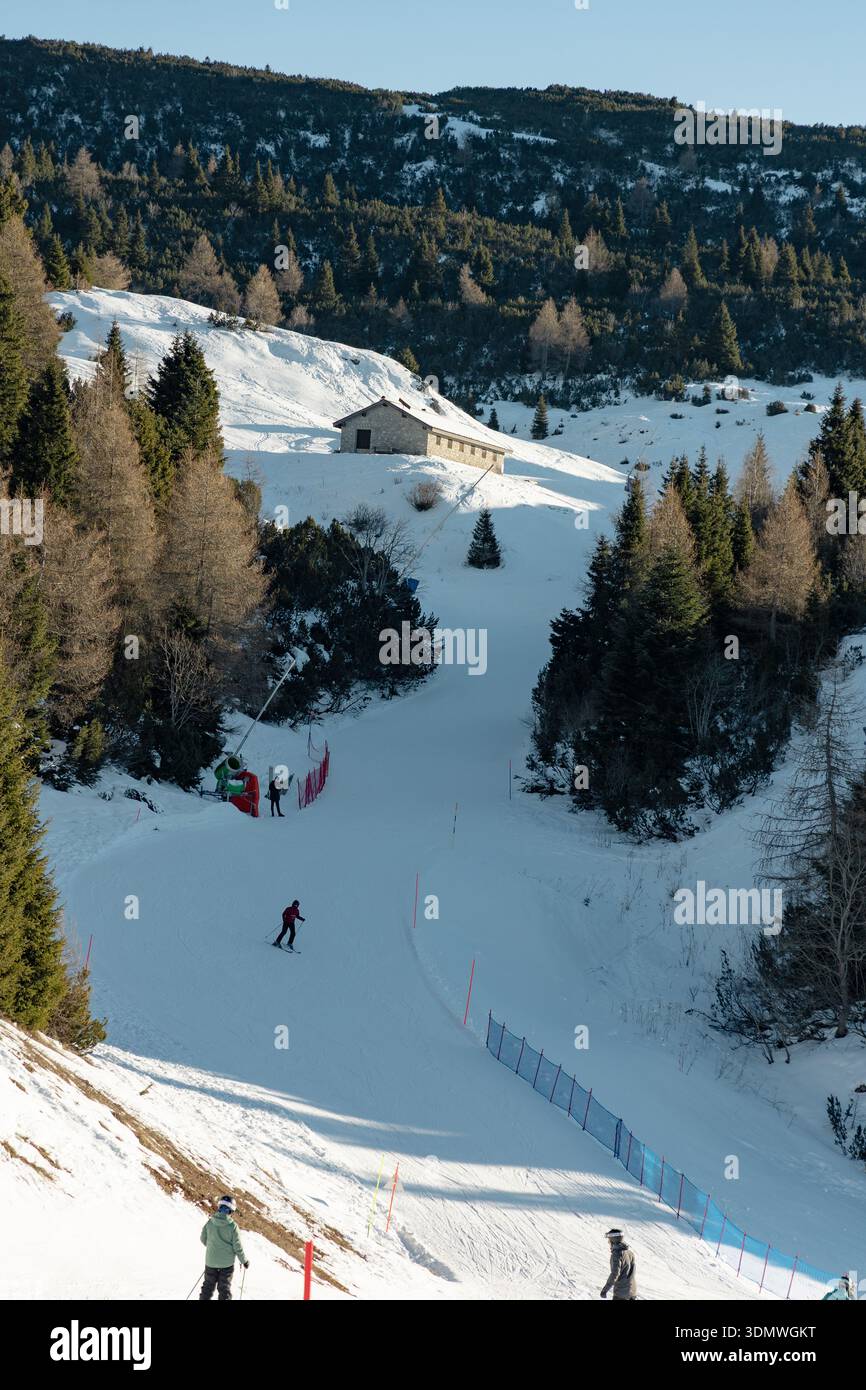 Skieurs sur une piste alpine ensoleillée dans une station de ski d'hiver, profitant d'une journée claire dans les montagnes. Italie. Banque D'Images