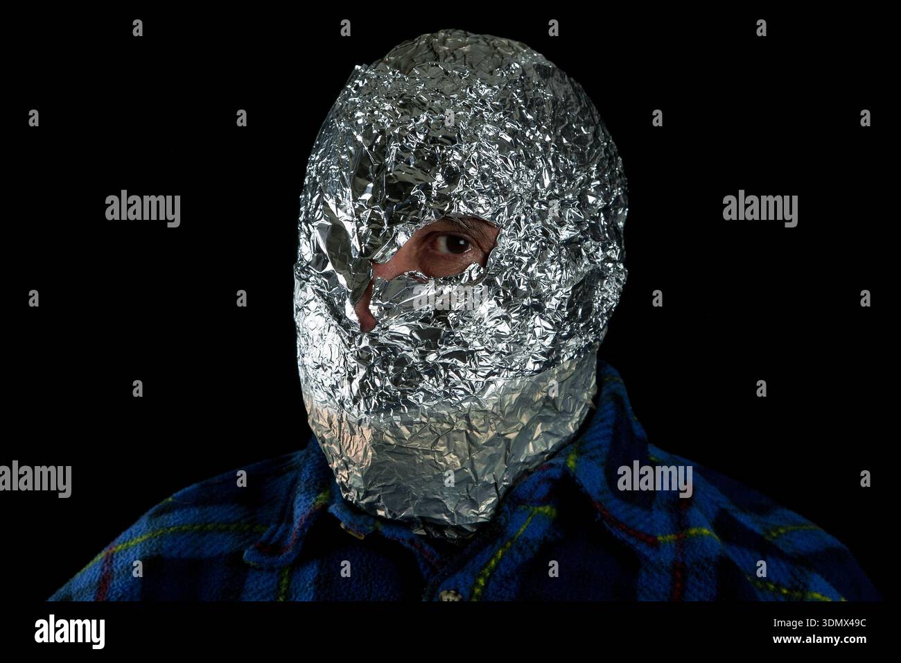 Portrait d'une personne anonyme portant un masque en aluminium sur fond noir. Banque D'Images