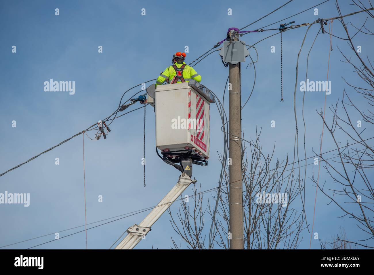 Bergame, Italie, 27 janvier 2026 : technicien électrique effectue la maintenance d'une ligne électrique aérienne à l'aide d'une plate-forme élévatrice. Il travaille en hauteur sur e. Banque D'Images