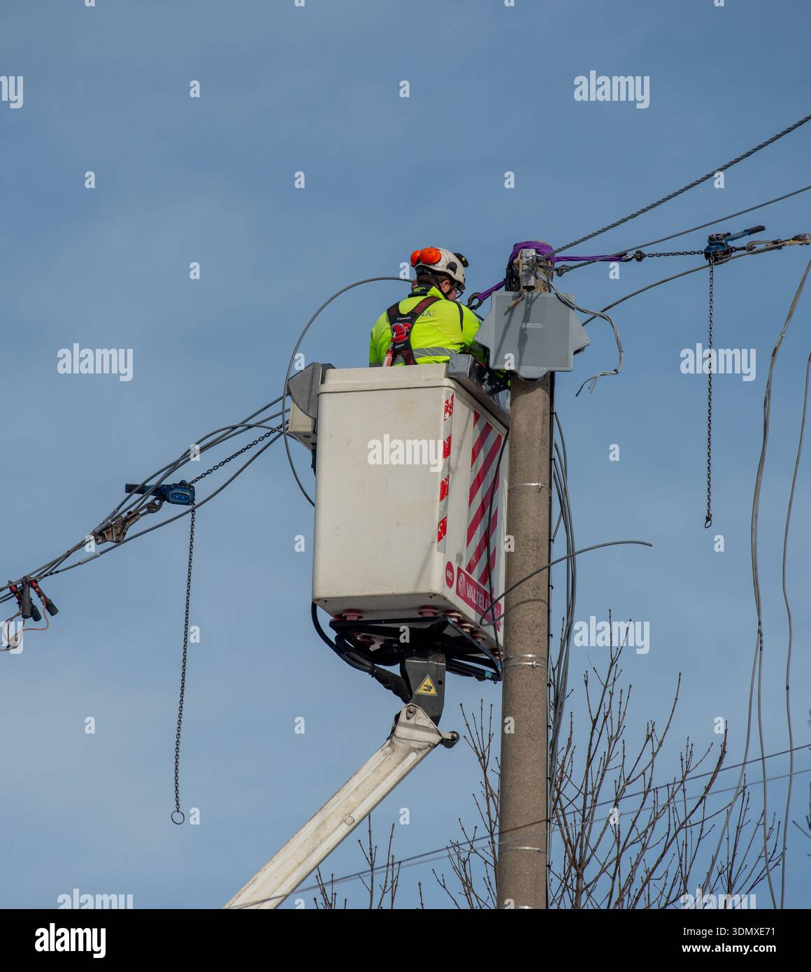 Bergame, Italie, 27 janvier 2026 : technicien électrique effectue la maintenance d'une ligne électrique aérienne à l'aide d'une plate-forme élévatrice. Il travaille en hauteur sur e. Banque D'Images