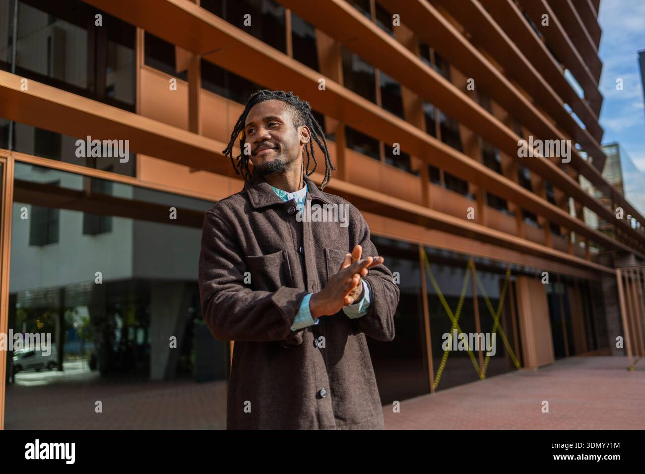 Homme d'affaires afro-américain avec des dreadlocks debout avec confiance à l'extérieur d'un immeuble de bureaux moderne, reflétant le professionnalisme et le succès dans le bu urbain Banque D'Images