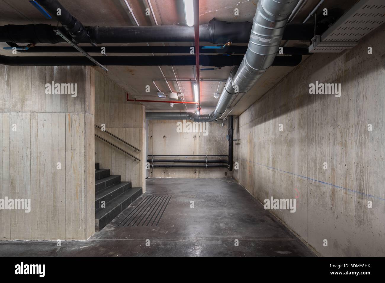 Une vue d’un système de ventilation industriel mis en valeur dans un sous-sol en béton. Les conduits visibles indiquent une infrastructure HVAC complexe nécessaire pour cl Banque D'Images