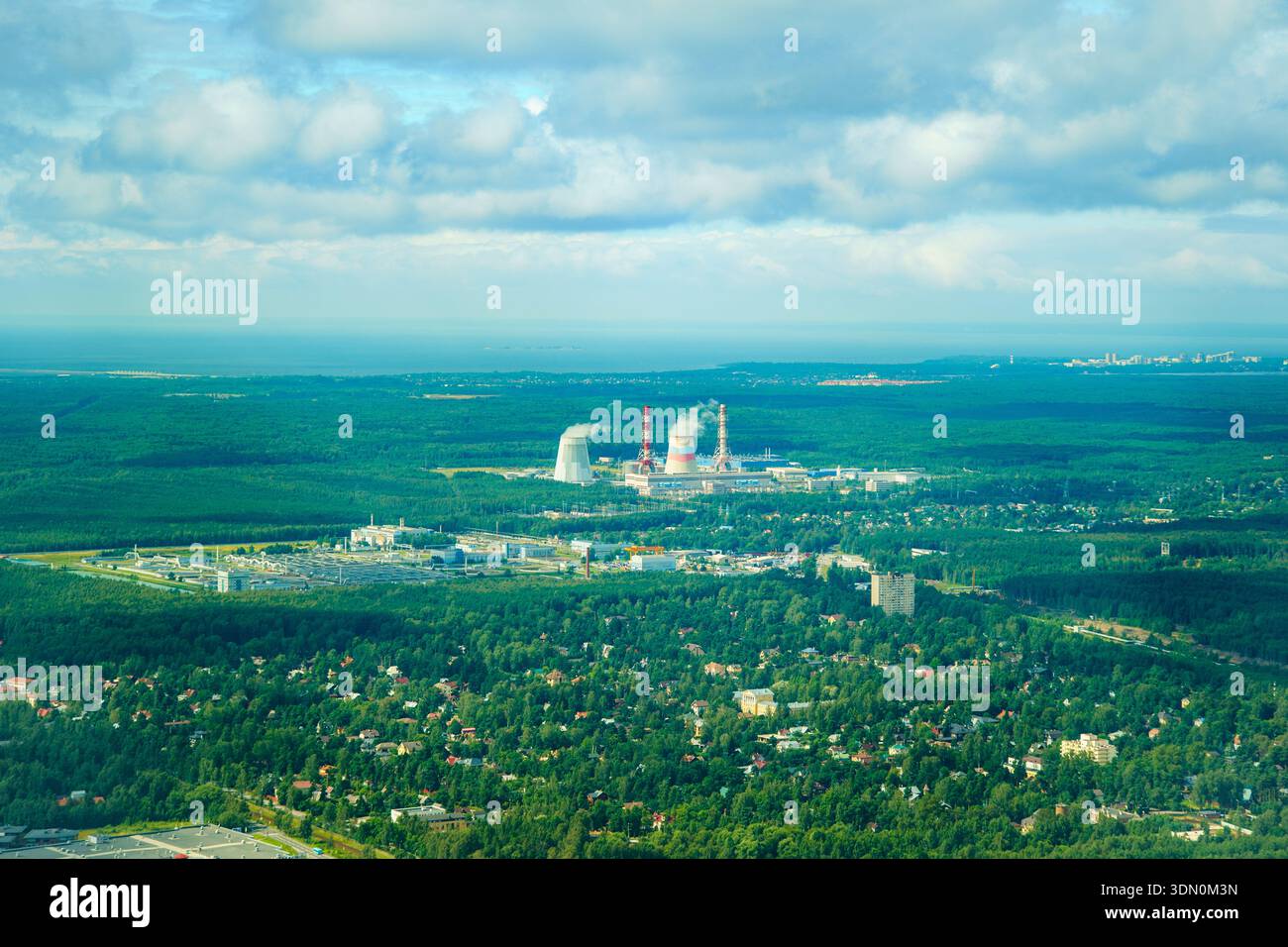Russie, Sosnovy Bor - 02 août 2025 : les tours de refroidissement de la centrale nucléaire de Leningrad émettent de la vapeur blanche dans le ciel au-dessus de la forêt verte. Banque D'Images