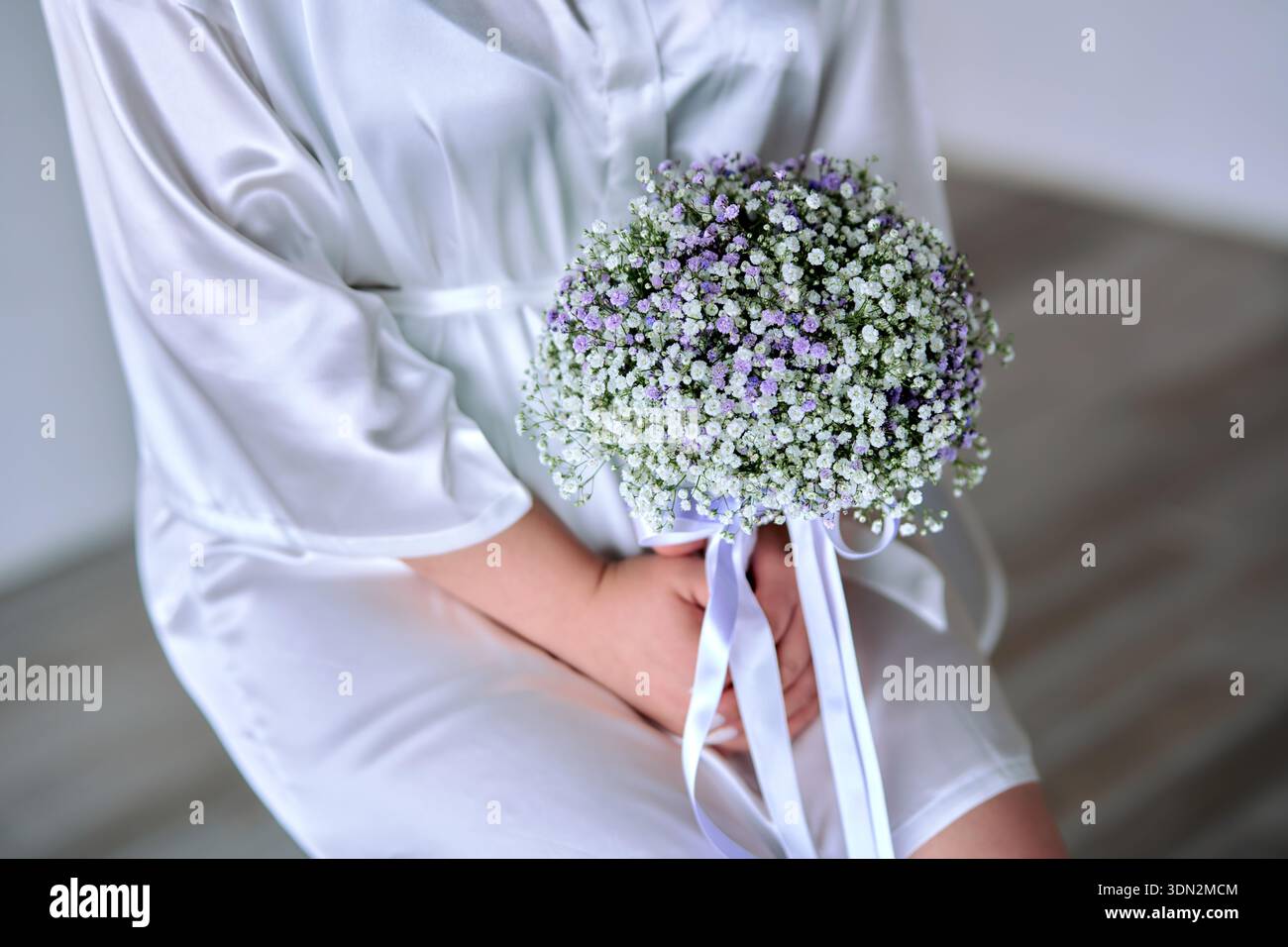 Mariée assise sur la chaise tenant bouquet de mariage Banque D'Images