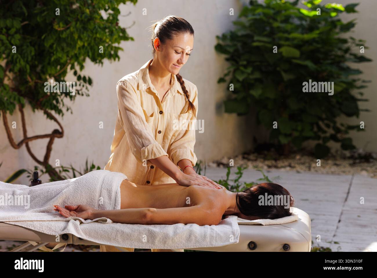 Thérapeute professionnel effectuant un massage relaxant du dos en extérieur. Thérapie de spa de bien-être pour la publicité et le marketing de site Web. Banque D'Images