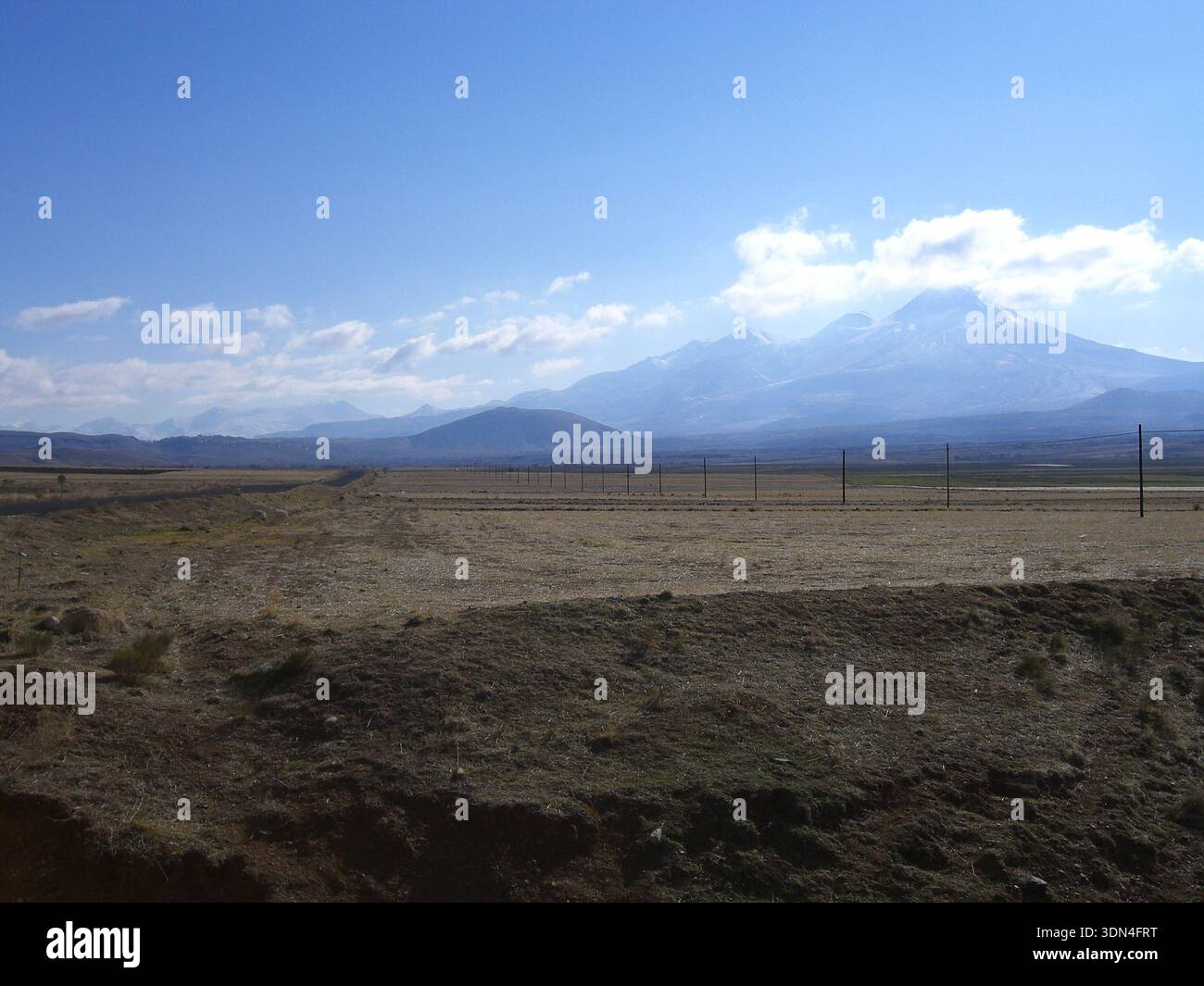 Vue lointaine du mont Hasan s'élevant au-dessus du paysage anatolien plat sous le ciel bleu. Banque D'Images