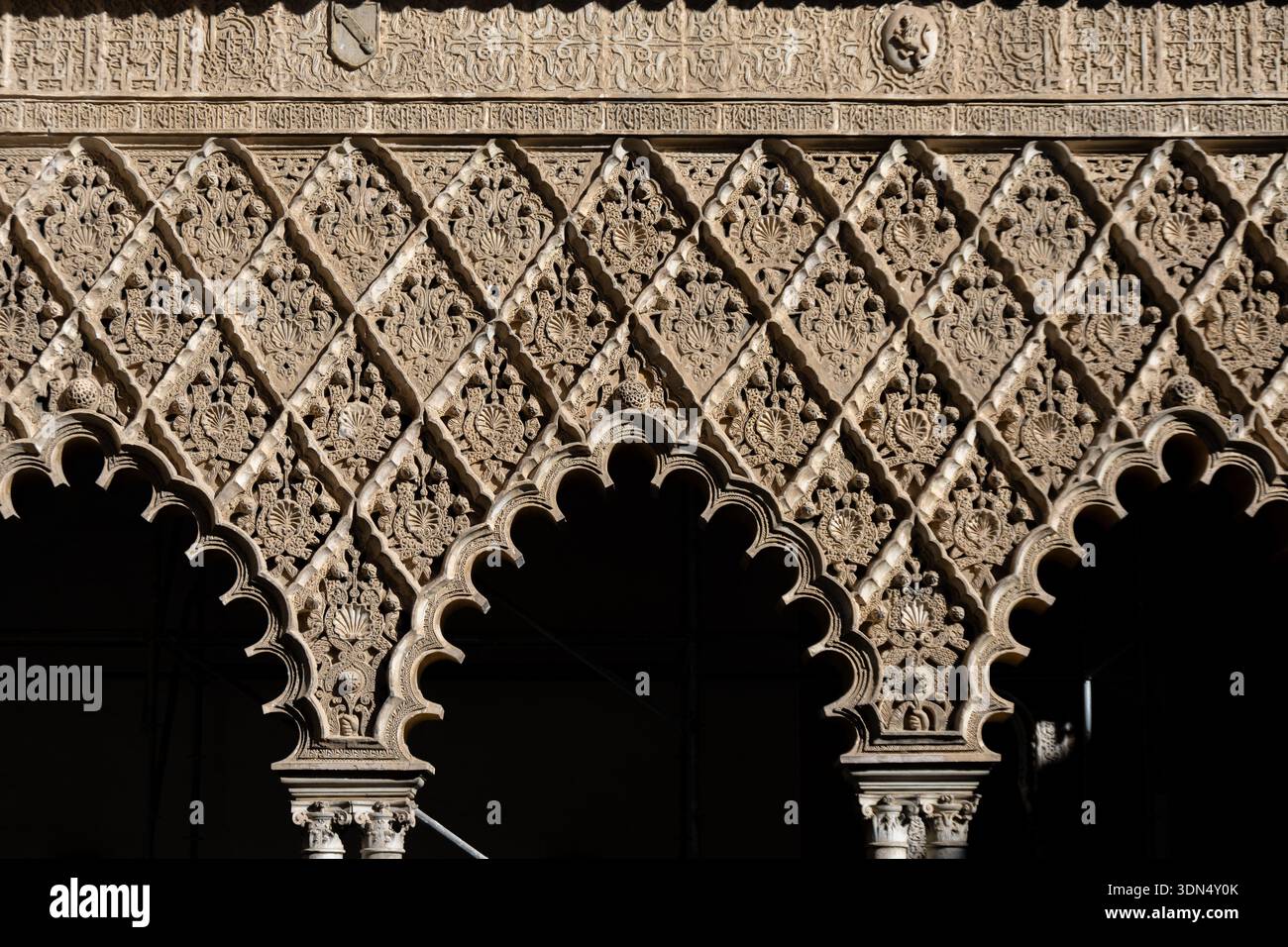 Gros plan de décorations murales en stuc ornées à l'intérieur du véritable Alcázar de Séville, mettant en valeur l'artisanat mudéjar et les motifs islamiques. Banque D'Images